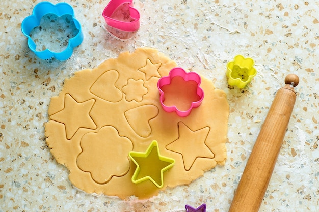 Rolled dough with colorful cookie cutters