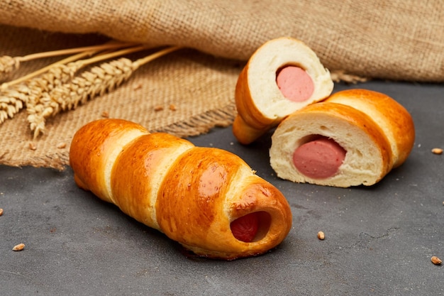 Rolled hot dog sausages in the dough baked in puff pastry on dark background