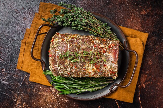 Rolled meat pork roulade with rosemary and thyme Dark background Top view