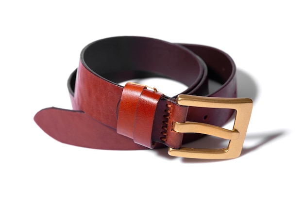 A rolledup brown leather belt with a metal buckle on a white background is isolated