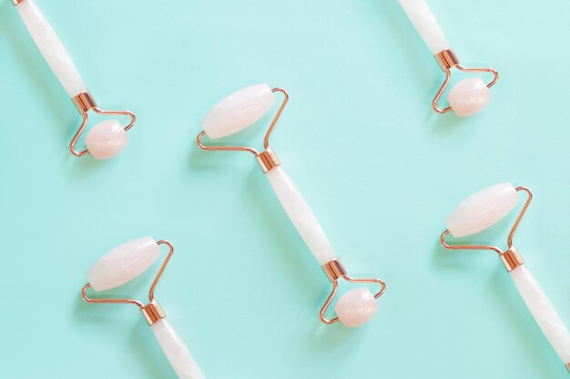 Rollers for facial massage made of rose quartz on a blue background located side by side