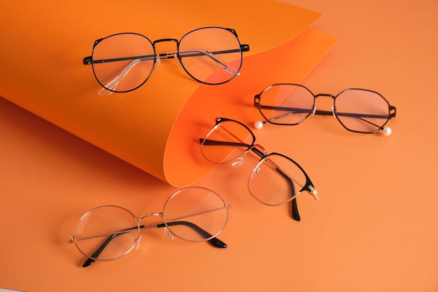 Rolles orange paper and several pairs of stylish glasses eyeglass frames in fashion trend bright colors