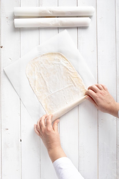 Photo rolling phyllo dough for apple strudel in a sheet of kitchen paper