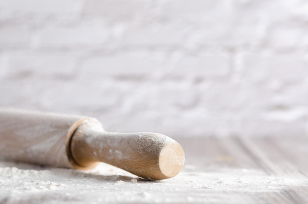 A rolling pin with white flour on wooden background with copy space.