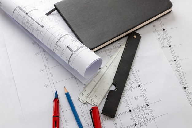 Rolls of architecture blueprints and house plans on the table and architect drawing tools.