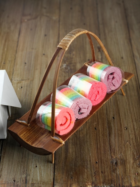 Rolls of colorful sponge cake on a wooden plate