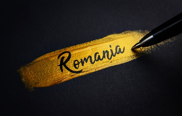 Photo romania handwriting text on golden paint brush stroke