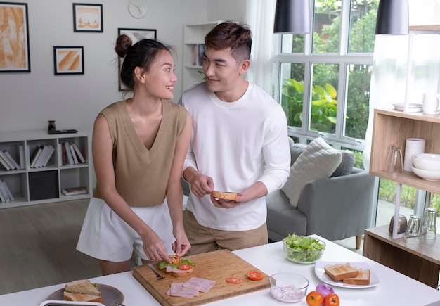 Romantic Asian couple is cooking on kitchen Happy young man and young woman are having fun together while prepare food Couple lifestyle concept