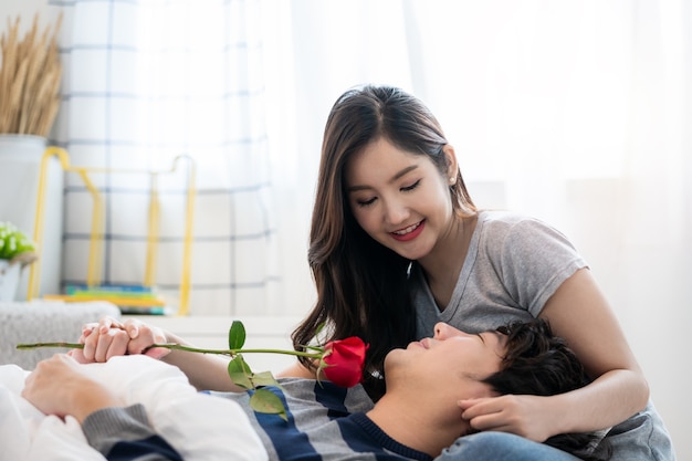 romantic asian couples in bedroom a young man giving red rose to pretty woman