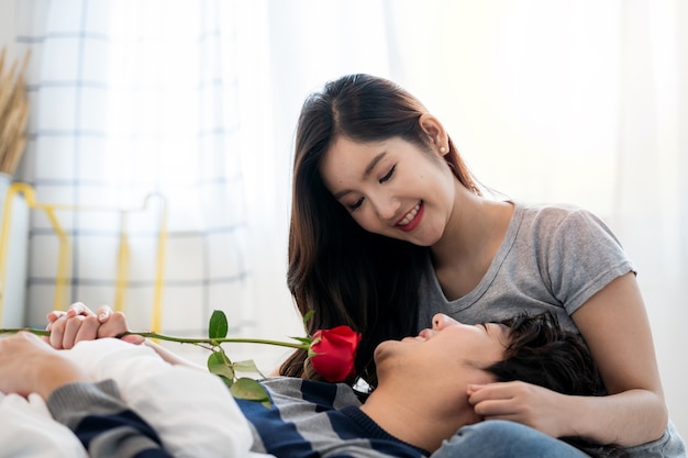 romantic asian couples in bedroom a young man giving red rose to pretty woman