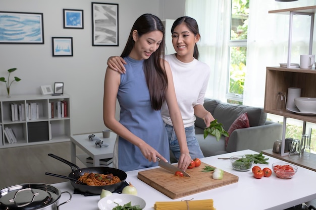 Romantic Asian lesbian couple is cooking on kitchen Lgbt lesbian couple are having fun together while preparing healthy food Healthy lifestyle concept