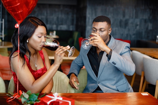 Romantic black couple sitting at restaurant wearing elegant clothes