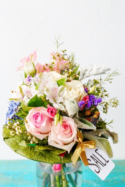 romantic bouquet of pink roses, lilies, green leaves on wooden blue table