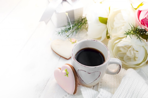 Romantic breakfast in bed. Coffee , cookies ,gift box and flower on wooden table. Valentine's day concept