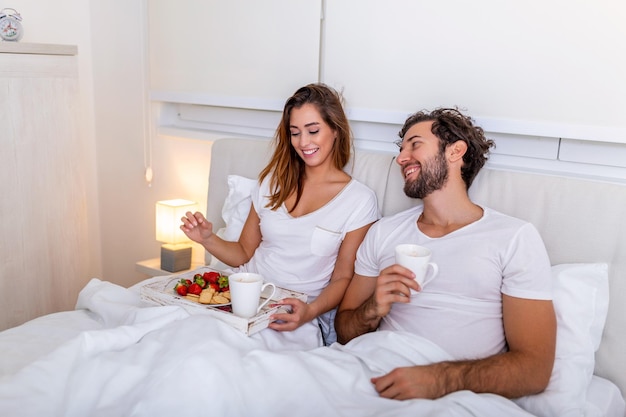 Romantic breakfast in bed on Valentines day man prepare for his woman she was very happy Young beautiful couple in bed having a breakfast and coffee in bed