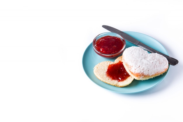 Romantic breakfast, heart-shaped bun and berry jam on white surface