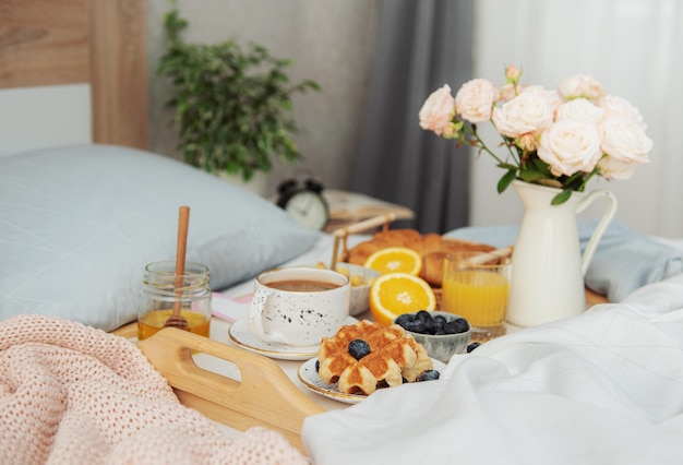 Romantic breakfast with coffee, waffles, orange juice and rose flowers.