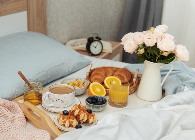 Romantic breakfast with coffee, waffles, orange juice and rose flowers.