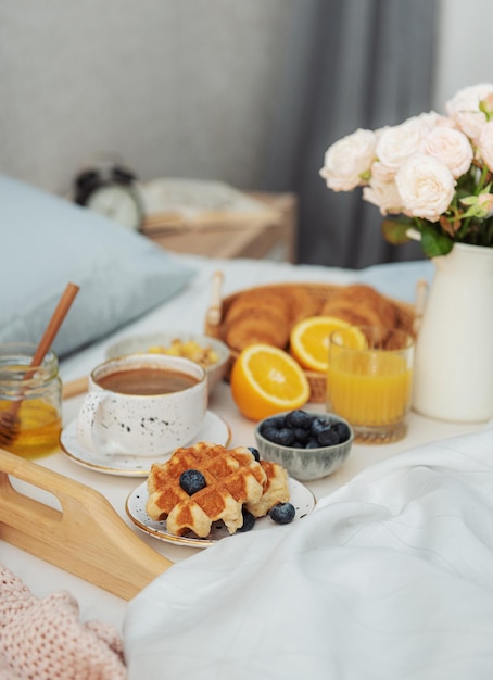 Romantic breakfast with coffee waffles orange juice and rose flowers