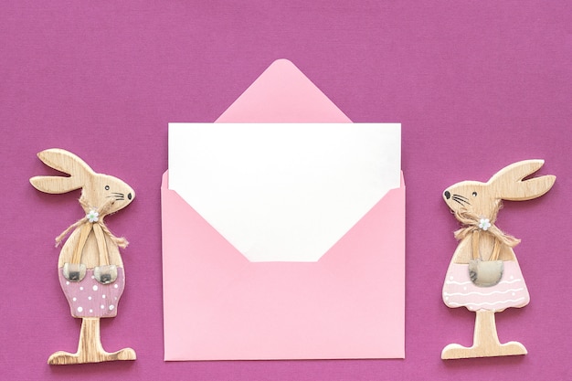 Romantic composition Pair of wooden lovers figurine rabbits and pink envelope 