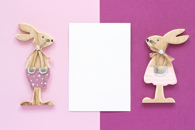 Romantic composition Pair of wooden lovers figurine rabbits and white blank card for text 