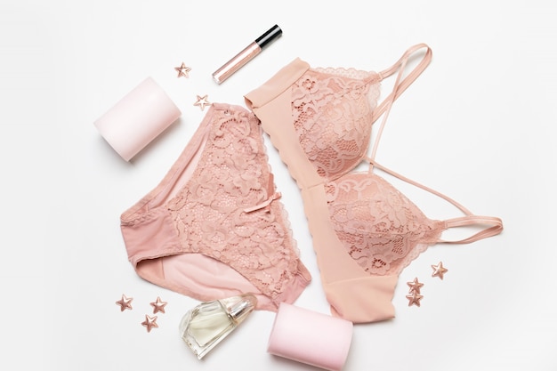 Romantic composition with female pink underwear, candle, lip gloss, perfume and stars