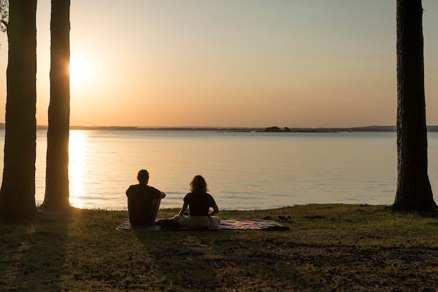 Romantic couple is resting at sunset on the shore of a forest lake Nature love relaxation concept