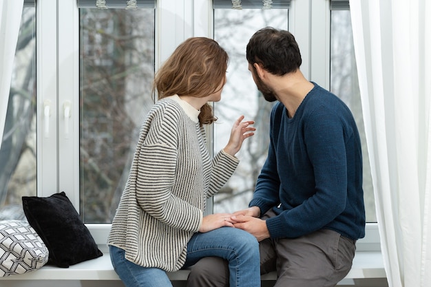 Romantic couple looking out of the window. Quarantine at home.