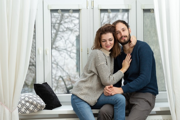 Romantic couple looking out of the window. Quarantine at home.