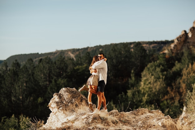 Romantic couple in love are standing and embracing on the stony mountain