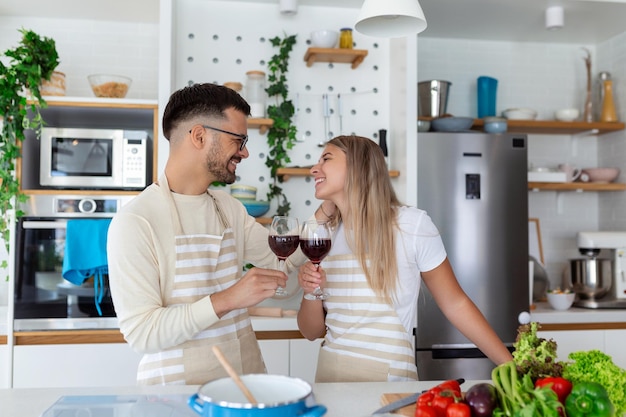 Romantic couple in love spending time together in kitchen Cute young couple drinking wine in kitchen and enjoying time together