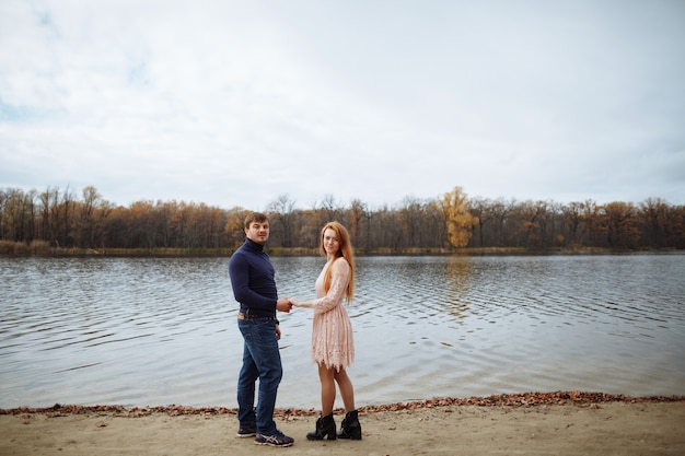 Romantic couple in love walking along the sandy shore near the lake