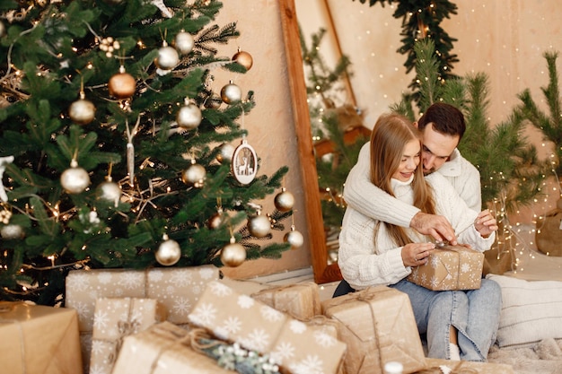 Romantic couple sitting on a floor near Christmas tree at home