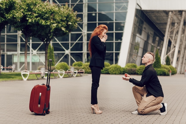 Romantic couple standing near the airport with a suitcase