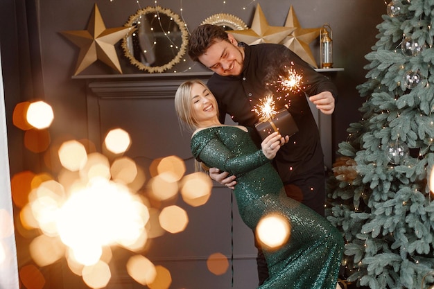 Romantic couple standing near Christmas tree holding a sparkler