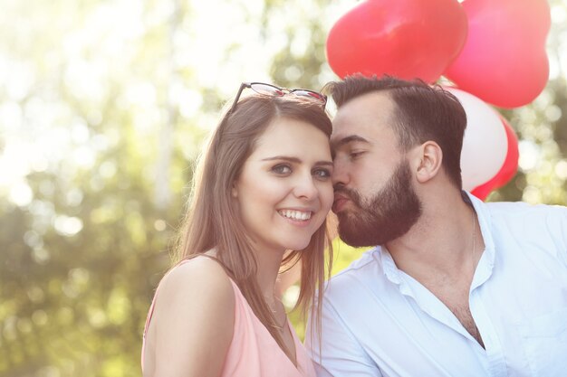 A romantic couple standing outside with baloons