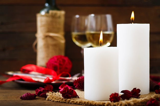 Romantic dinner setting with candles, wine and petals