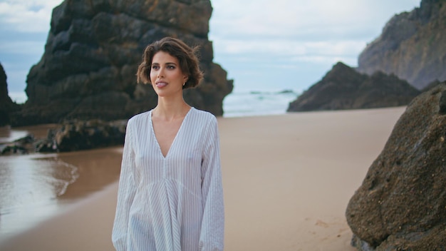 Romantic lady admiring beach on rocky island smiling woman walking sandy coast