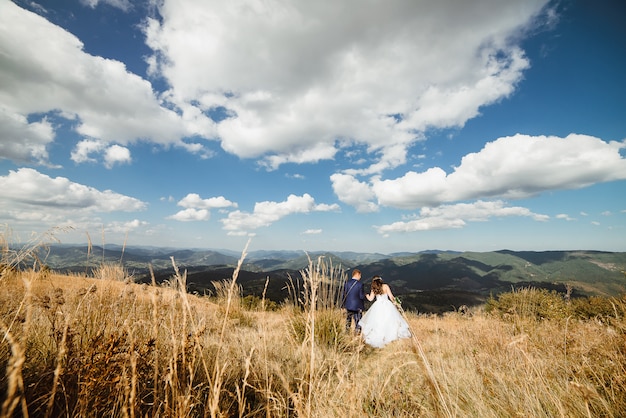 Romantic lovely wedding couple is looking into the distance in the mountains