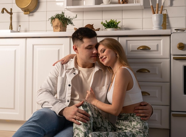 Romantic married couple sitting on kitchen floor and hugging Tender family moment