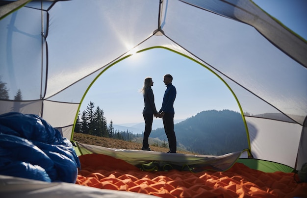 Romantic pair having rest in campsite at summer mountains