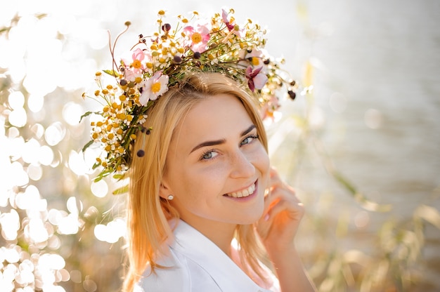 Romantic smiling blond girl in a wreath of flowers