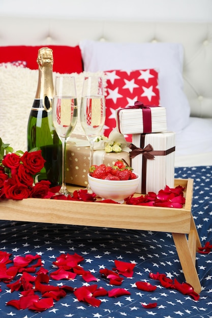 Romantic still life with champagne strawberry and roses on bed