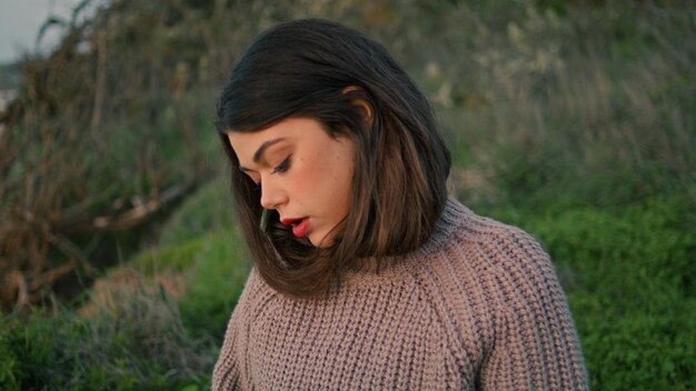 Romantic woman sitting grass in gray sweater close up girl relaxing on nature