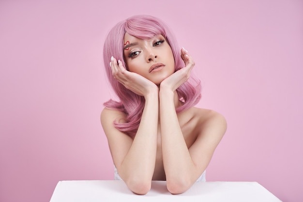 Romantic woman with dyed pink hair at table