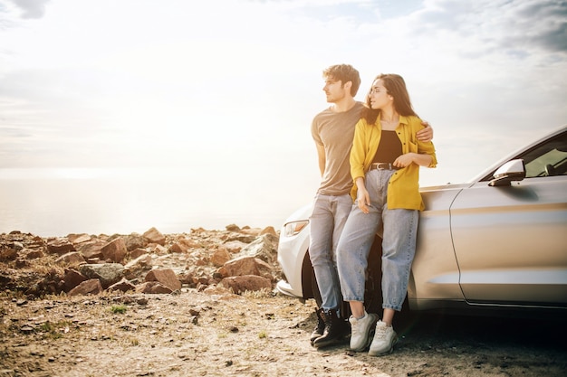 Romantic Young Attractive Couple Watching the Sunset and Kissing with Sports Car.