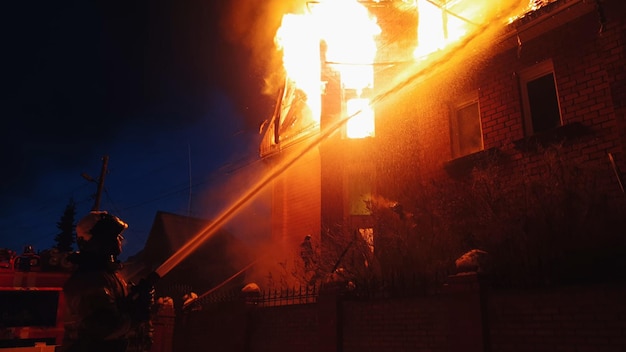 The roof of the house is on fire The residential building burn village Firefighters put out a fire from the crane from above Smoke and sparks