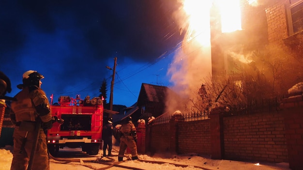 The roof of the house is on fire. The residential building burn, village. Firefighters put out a fire from the crane from above. Smoke and sparks.