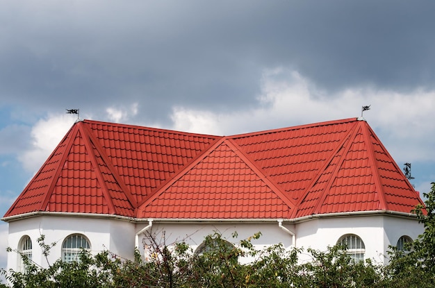 Roof made of light brown red metal tile metal roofing shingles against blue sky