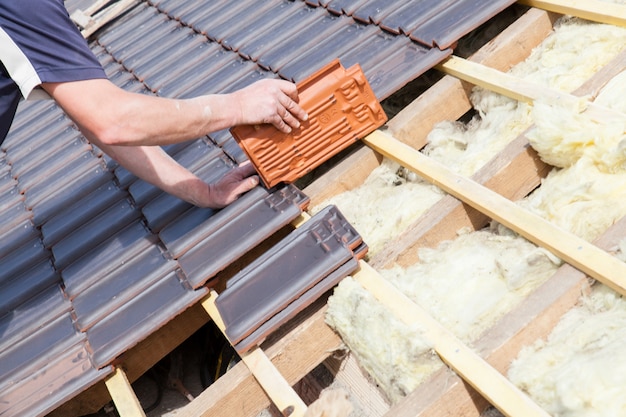 A roofer laying tile on the roof